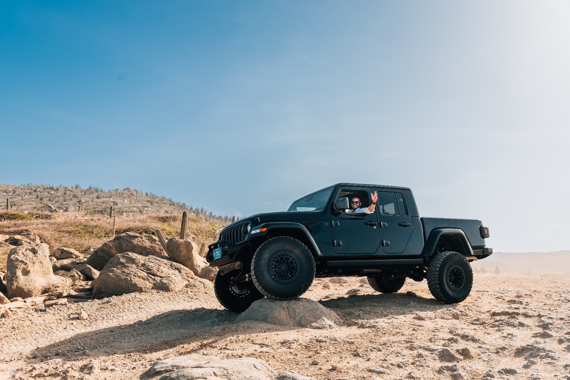 The Beast — a lifted matte black Jeep Gladiator on Aruba's rocky coast